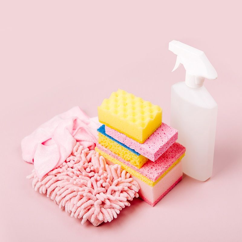 A Stack of Sponges , a Mop, and A Spray Bottle on A Pink Background — Maid In Bowral in Moss Vale, NSW