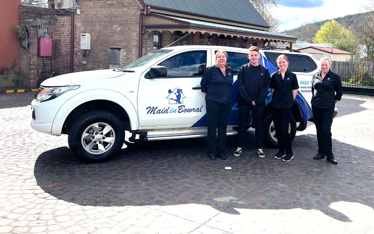 A Group of People Are Standing in Front of A White Truck — Maid In Bowral in Bowral, NSW