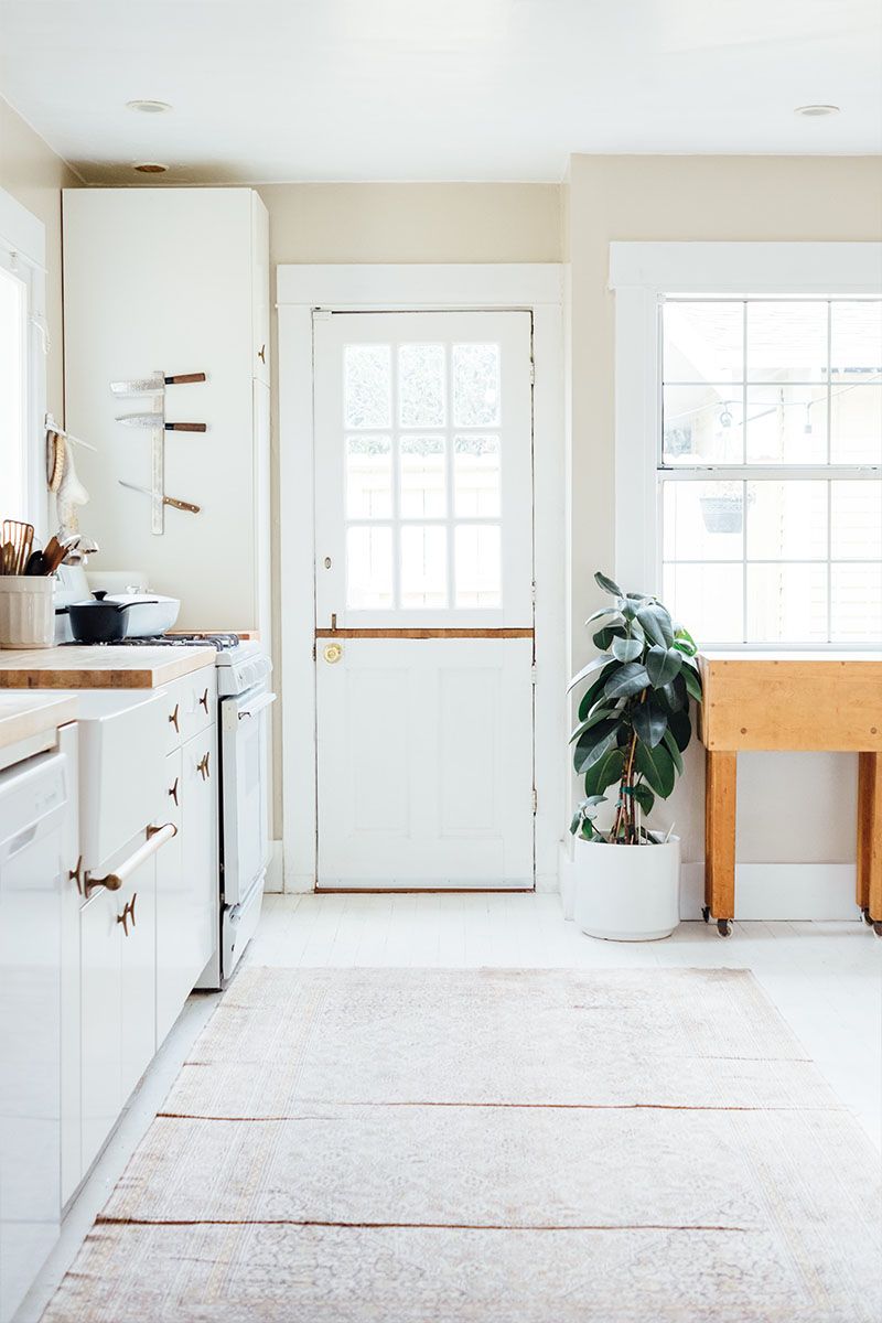 A Kitchen with White Cabinets, a Wooden Table and A Potted Plant — Maid In Bowral in Moss Vale, NSW