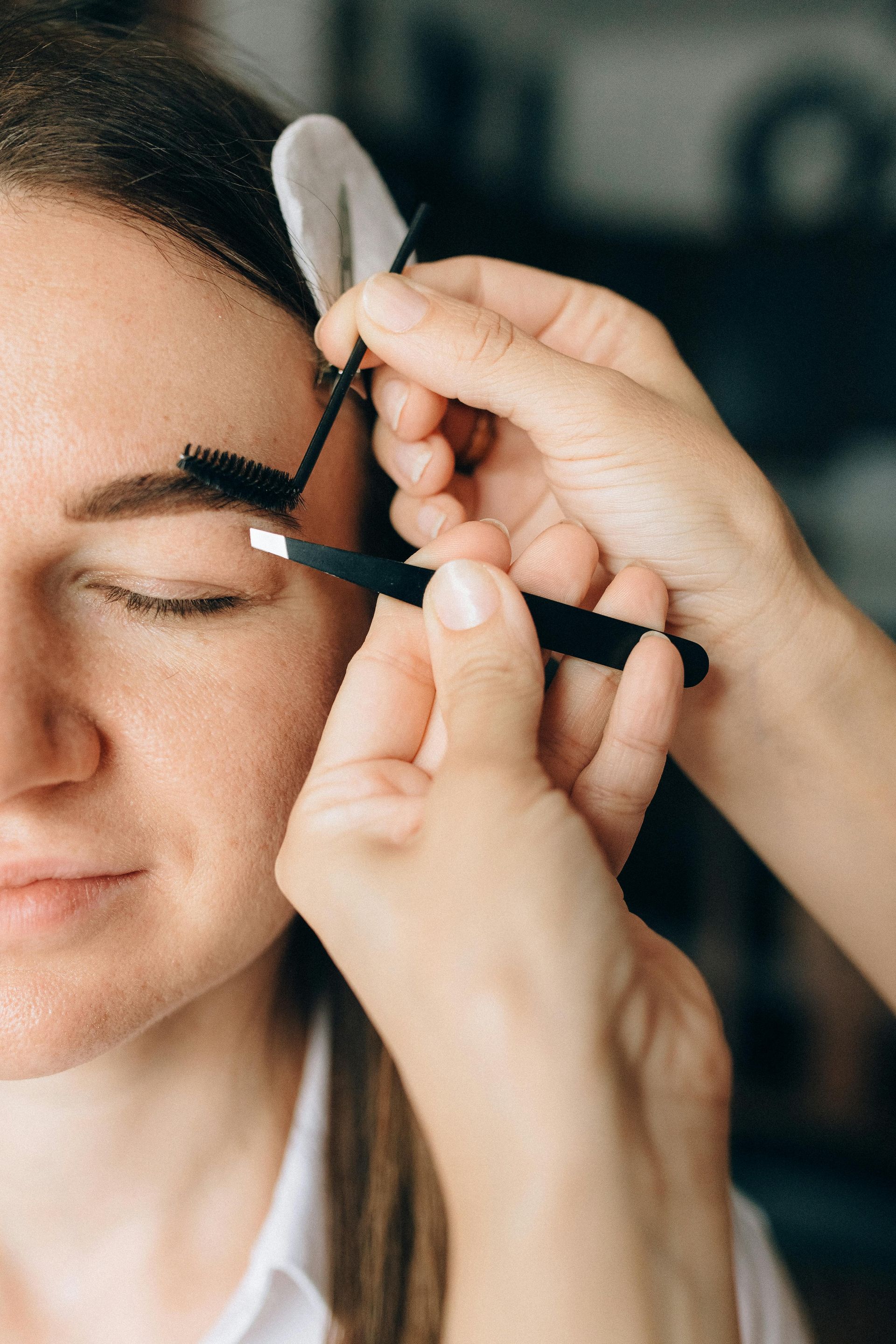 Person getting eyebrows tweezed with tweezers.