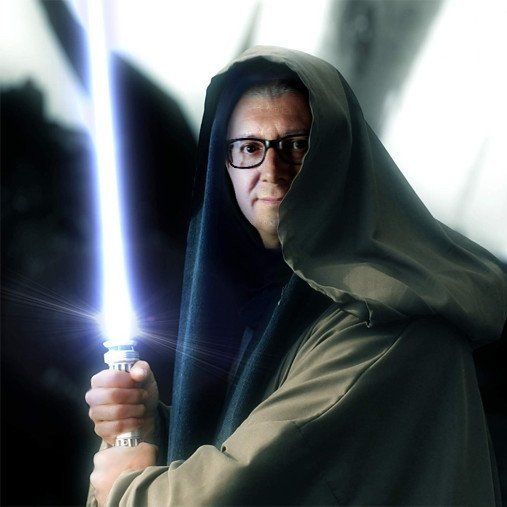 un uomo che indossa un cappello e occhiali tiene in mano una spada luminosa