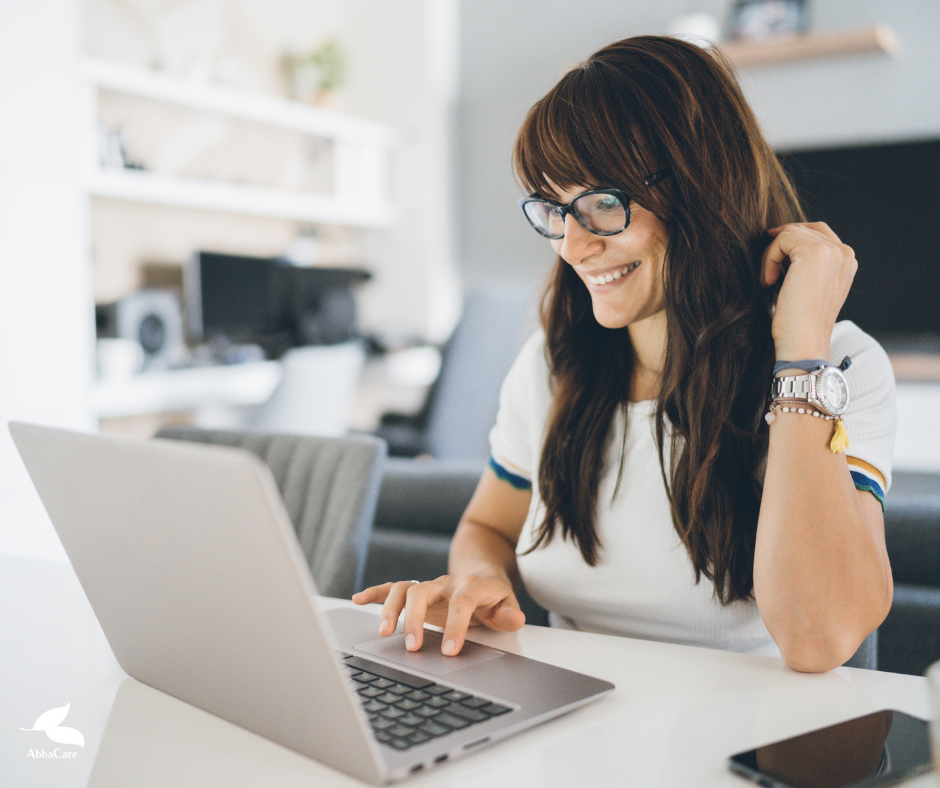 A woman is sitting at a table using a laptop computer.