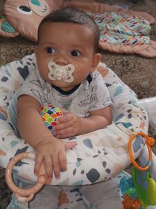 A baby is sitting in a high chair with a pacifier in his mouth.