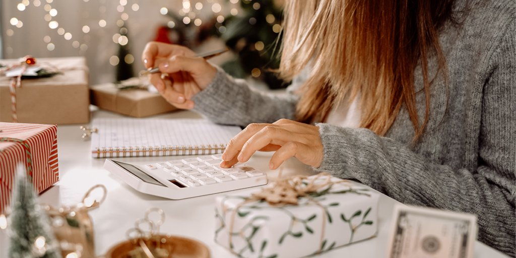 A woman is sitting at a desk using a calculator.