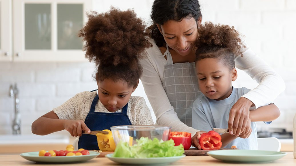 A woman and two children are preparing food in a kitchen.