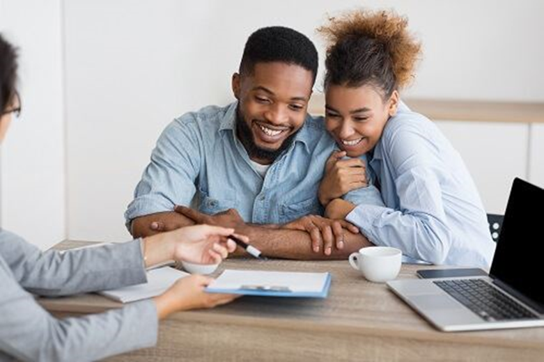 A man and a woman are sitting at a table with a laptop.