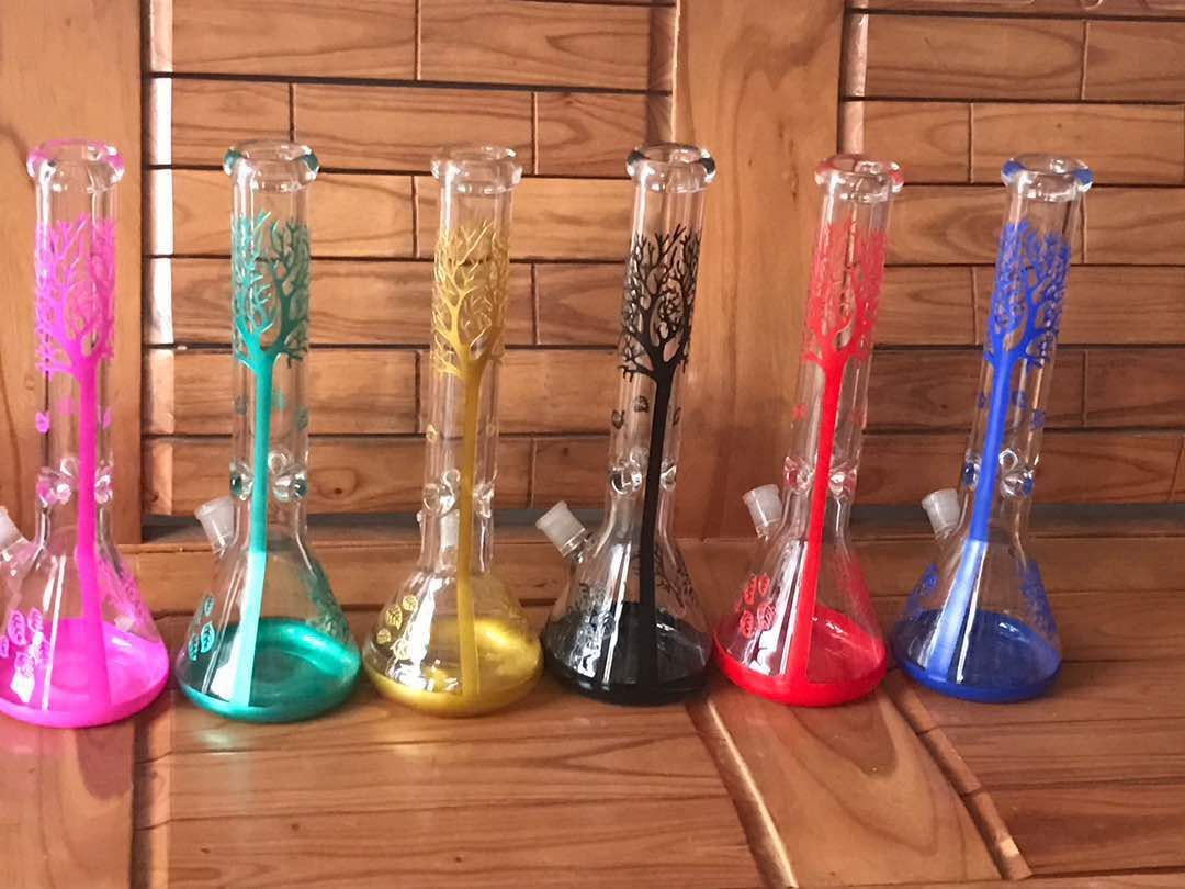 A row of beakers of different colors are sitting on a wooden table