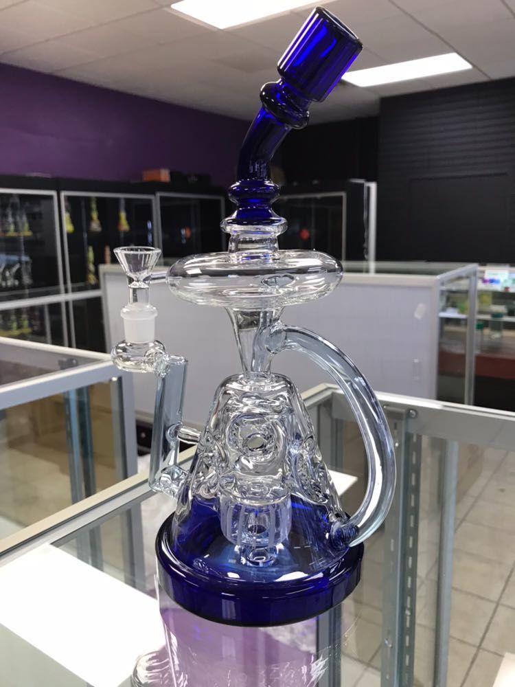 A blue glass pipe is sitting on top of a glass table in a store