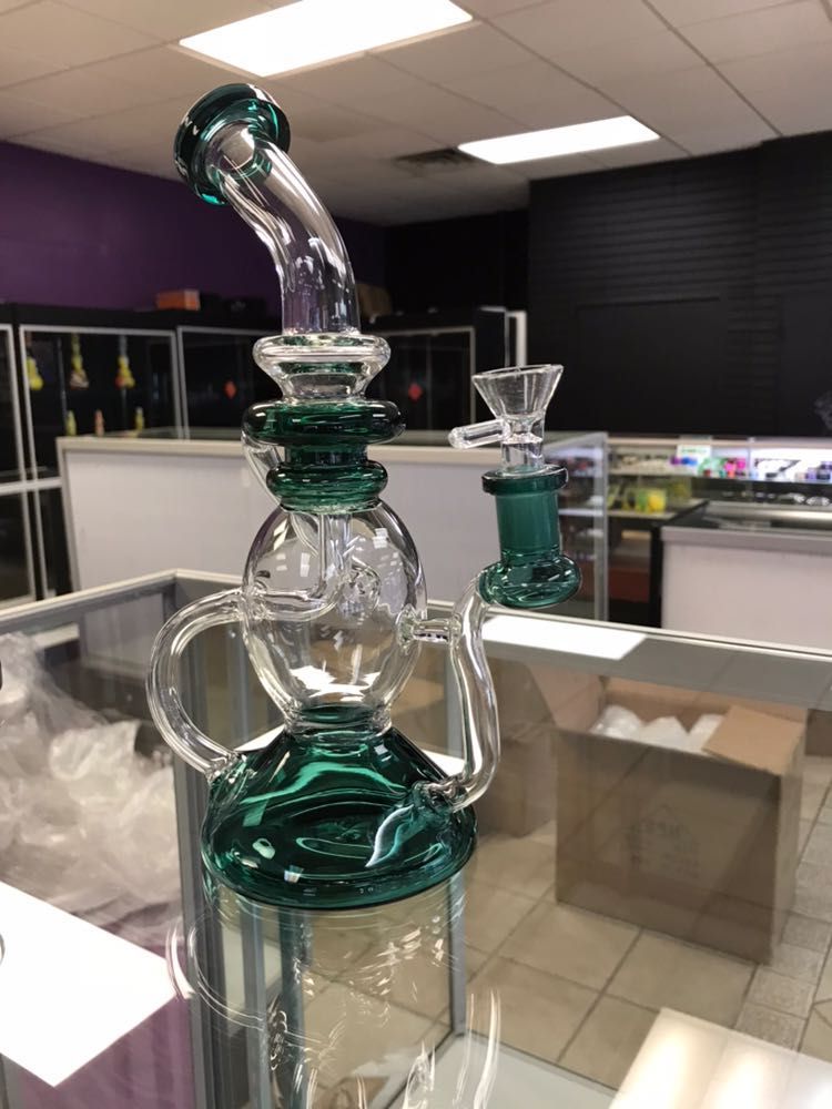 A green glass bong is sitting on top of a glass display case in a store