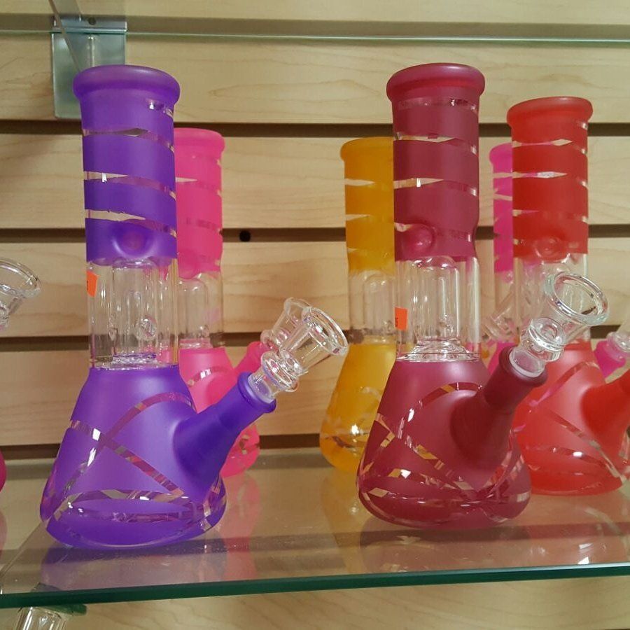 A bunch of different colored bongs on a glass shelf