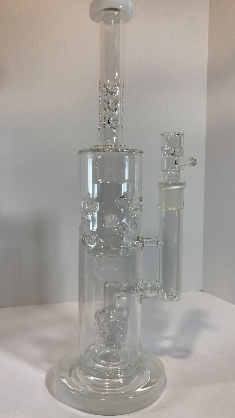 A clear glass bong is sitting on top of a white table