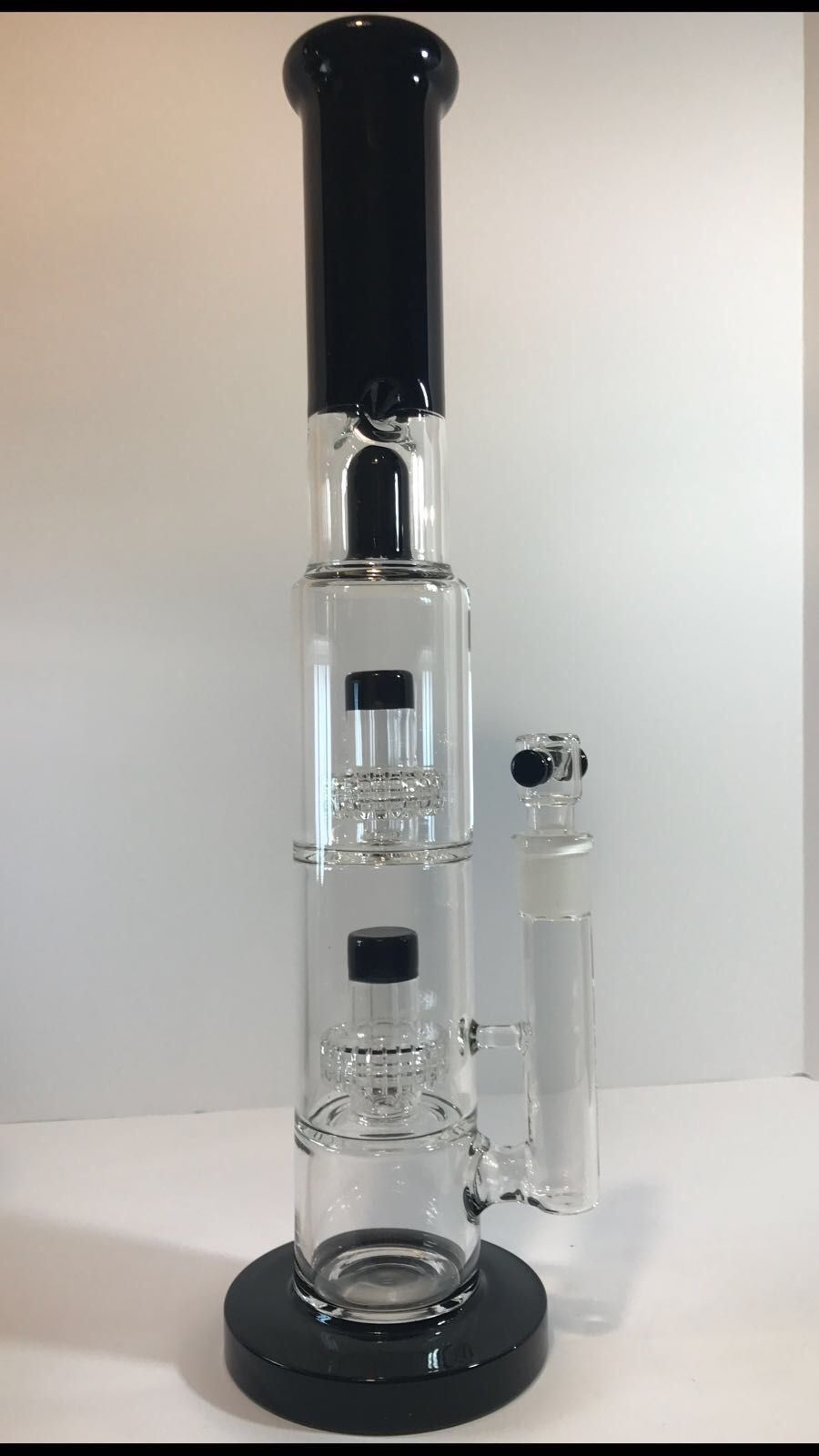 A black and clear glass bong is sitting on a white table