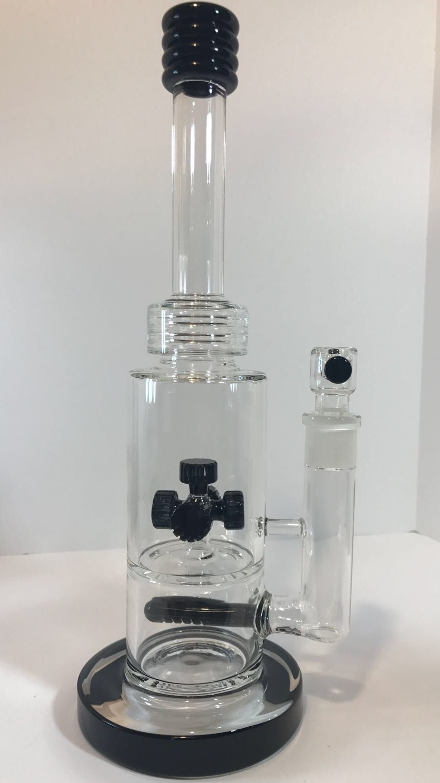 A glass pipe with a black top is sitting on a table