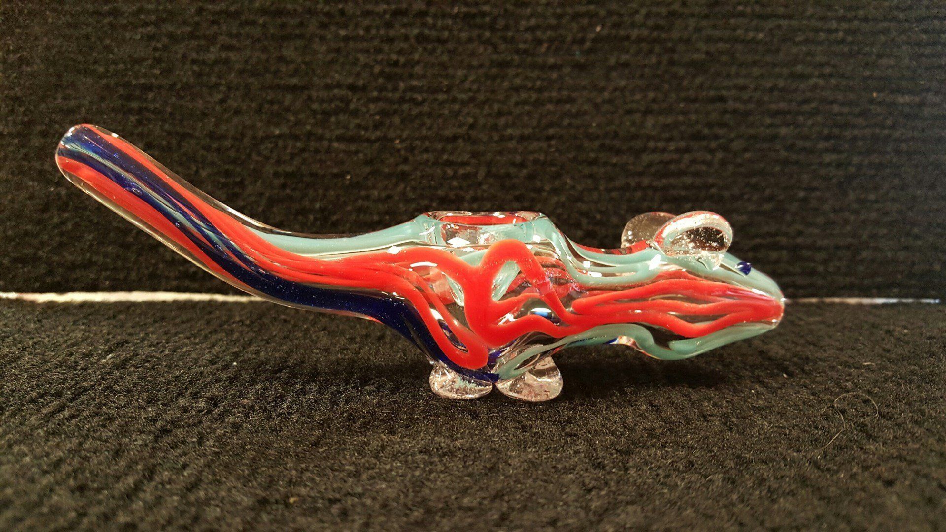 A glass pipe in the shape of a lizard is sitting on a table
