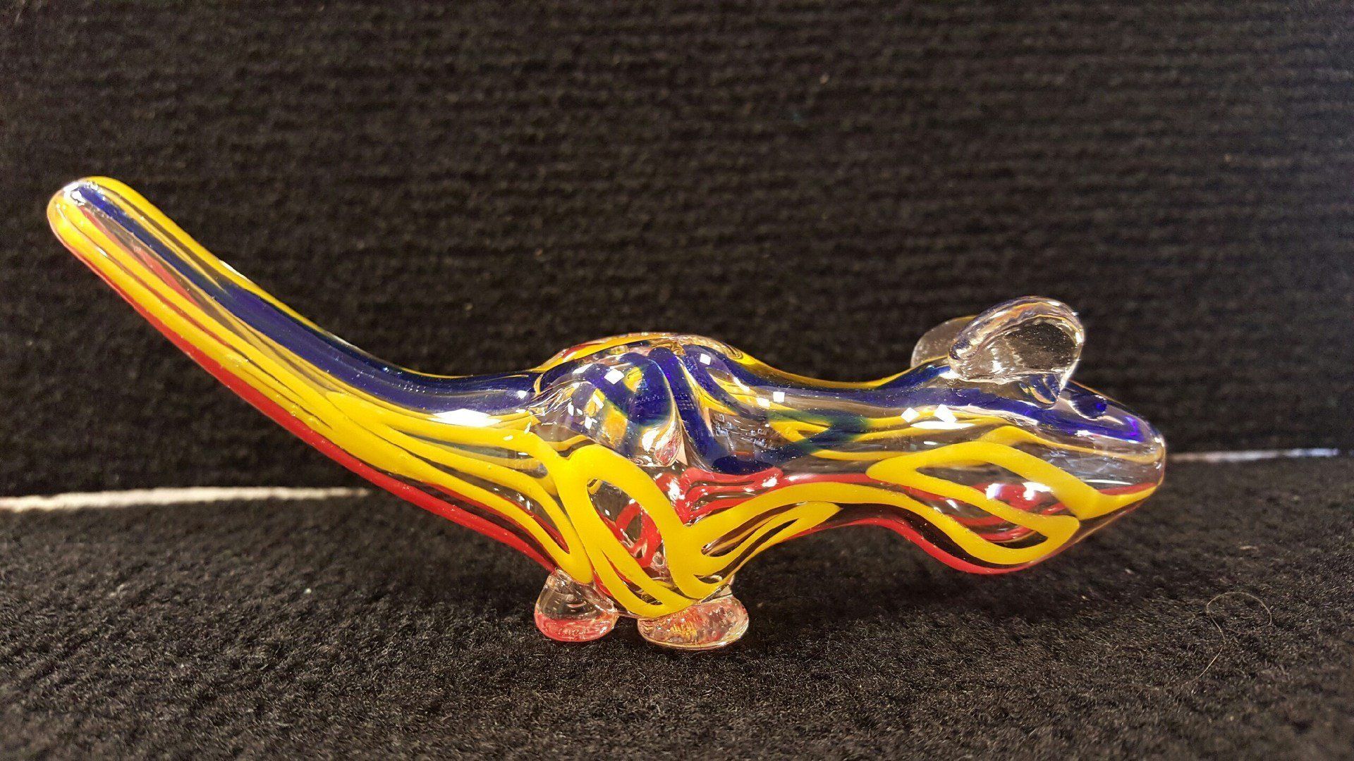 A colorful glass pipe is sitting on a black surface