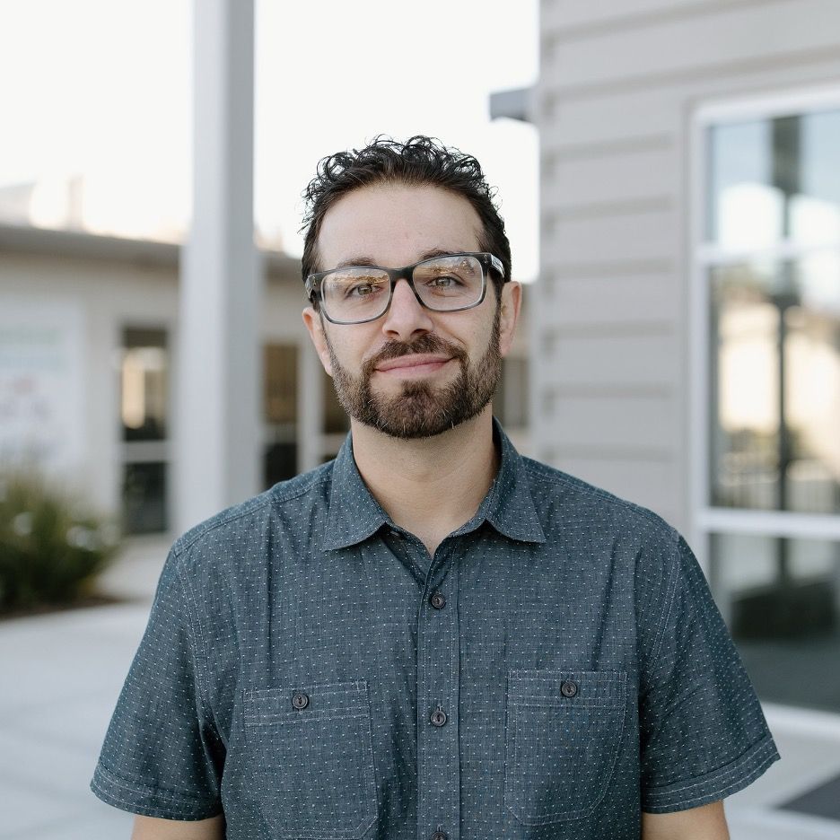 cody cannon lead pastor with glasses and a beard stands in front of a building