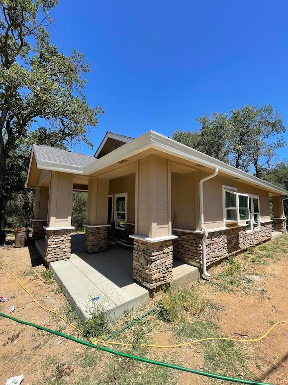 A house is being built in the middle of a field with a hose in front of it.