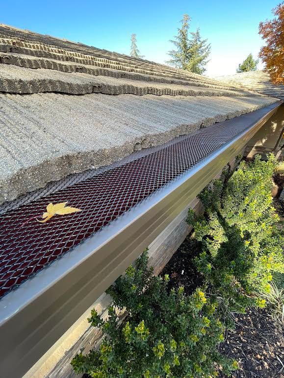 A close up of a gutter with a leaf on it.