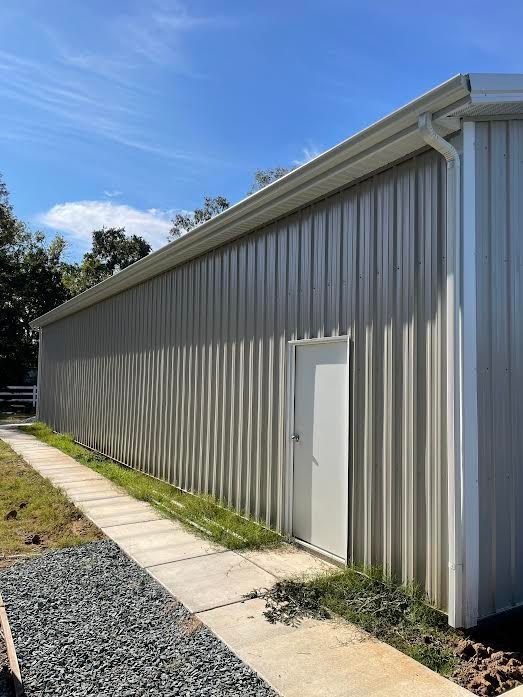 A large metal building with a white door and a walkway leading to it.