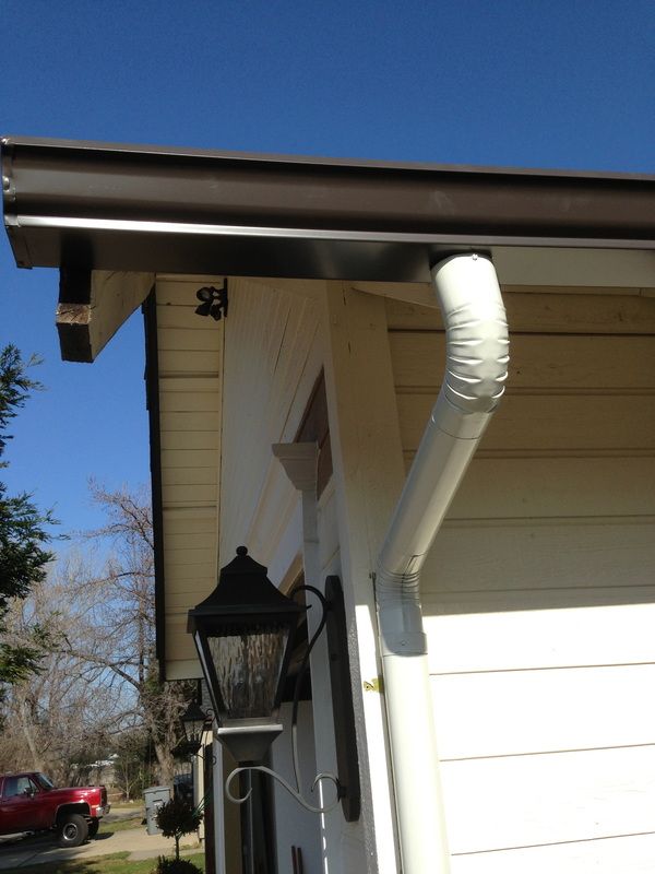 A white house with a brown gutter and a white drainpipe