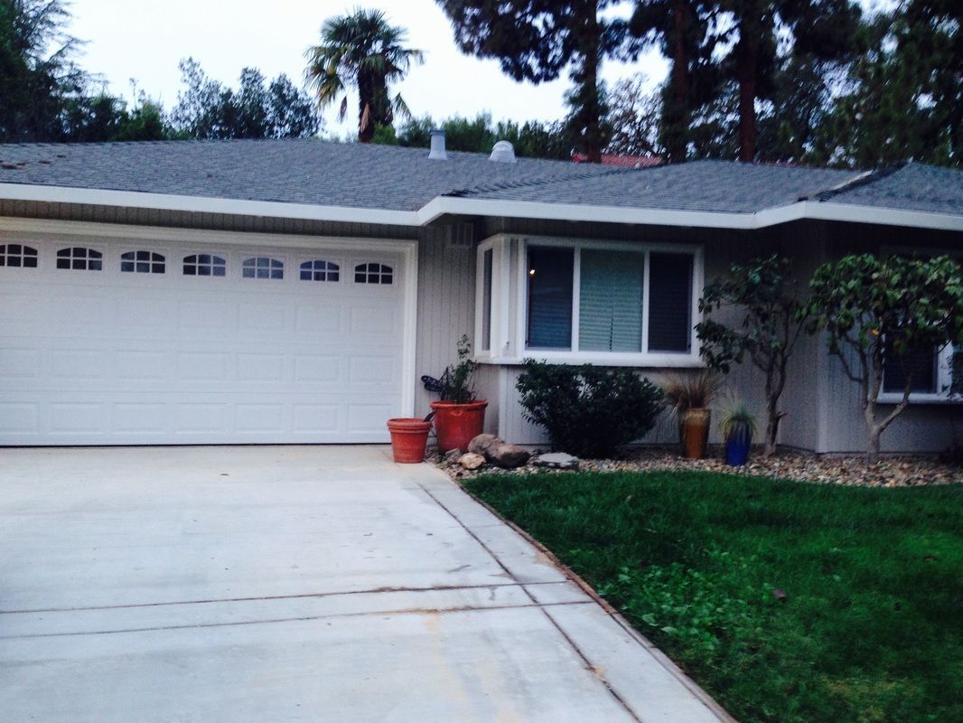 A white house with a gray roof and a white garage door
