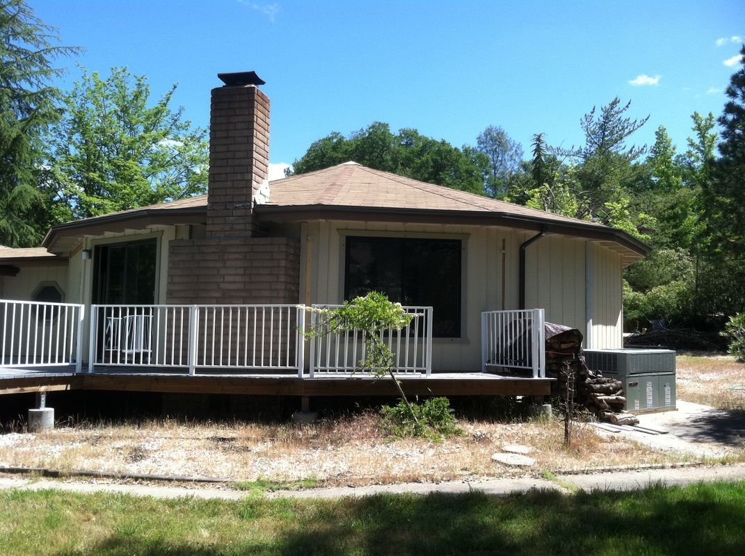 A white house with a brick chimney and a deck