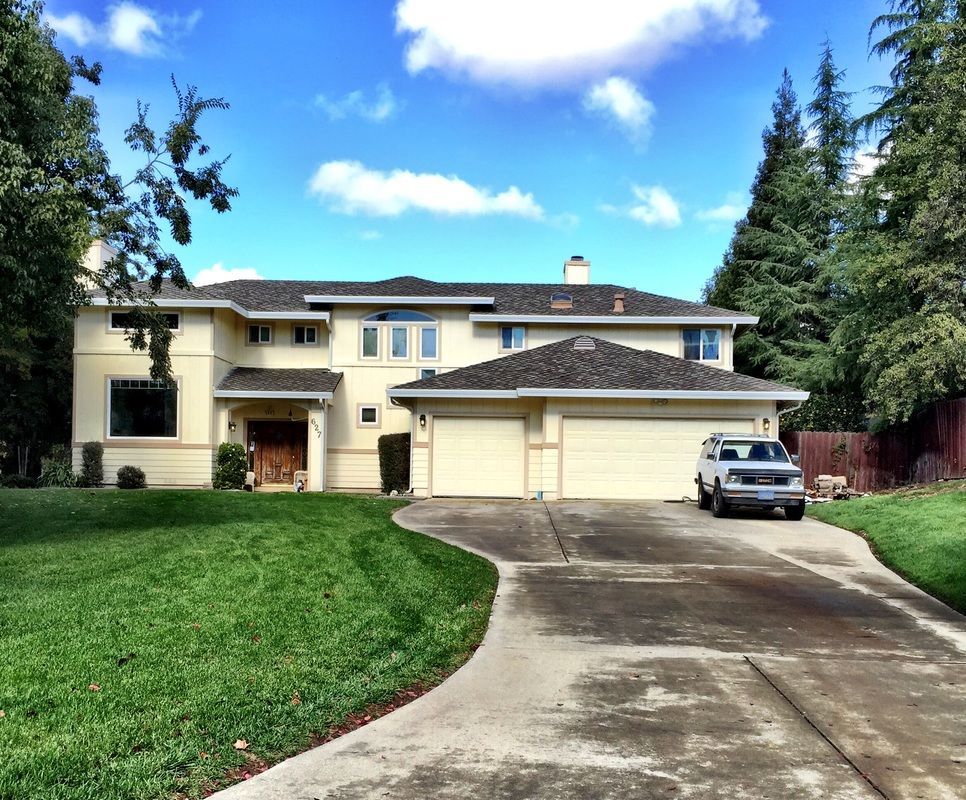 A white truck is parked in front of a large house