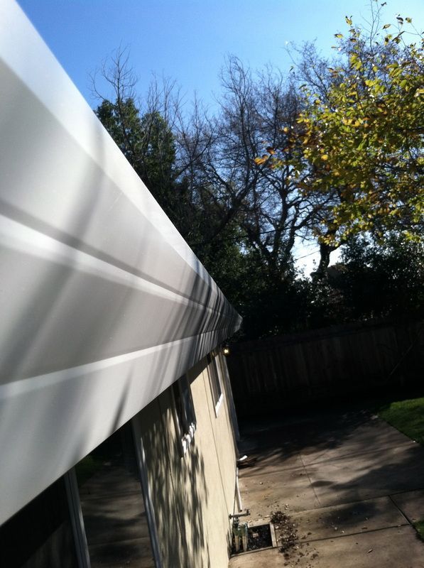 A white awning is hanging from the side of a house