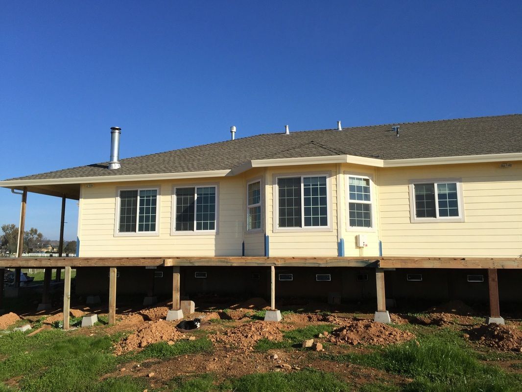 A house is being built on stilts in a field.