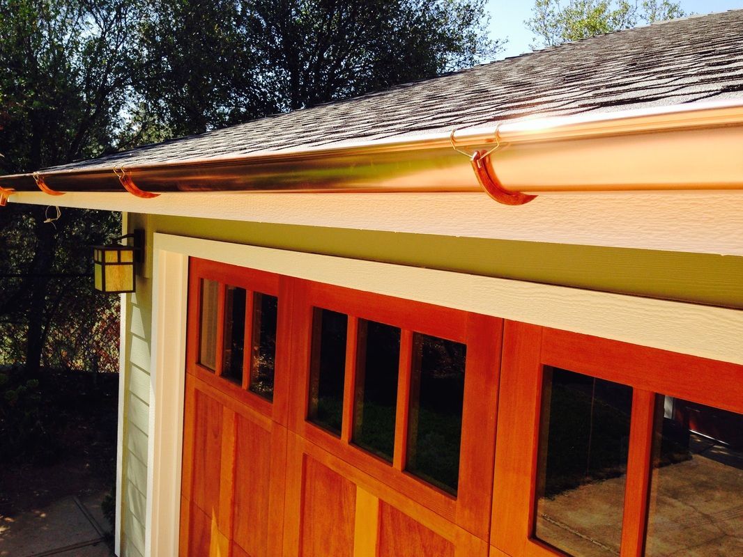 A garage with a wooden door and a copper gutter