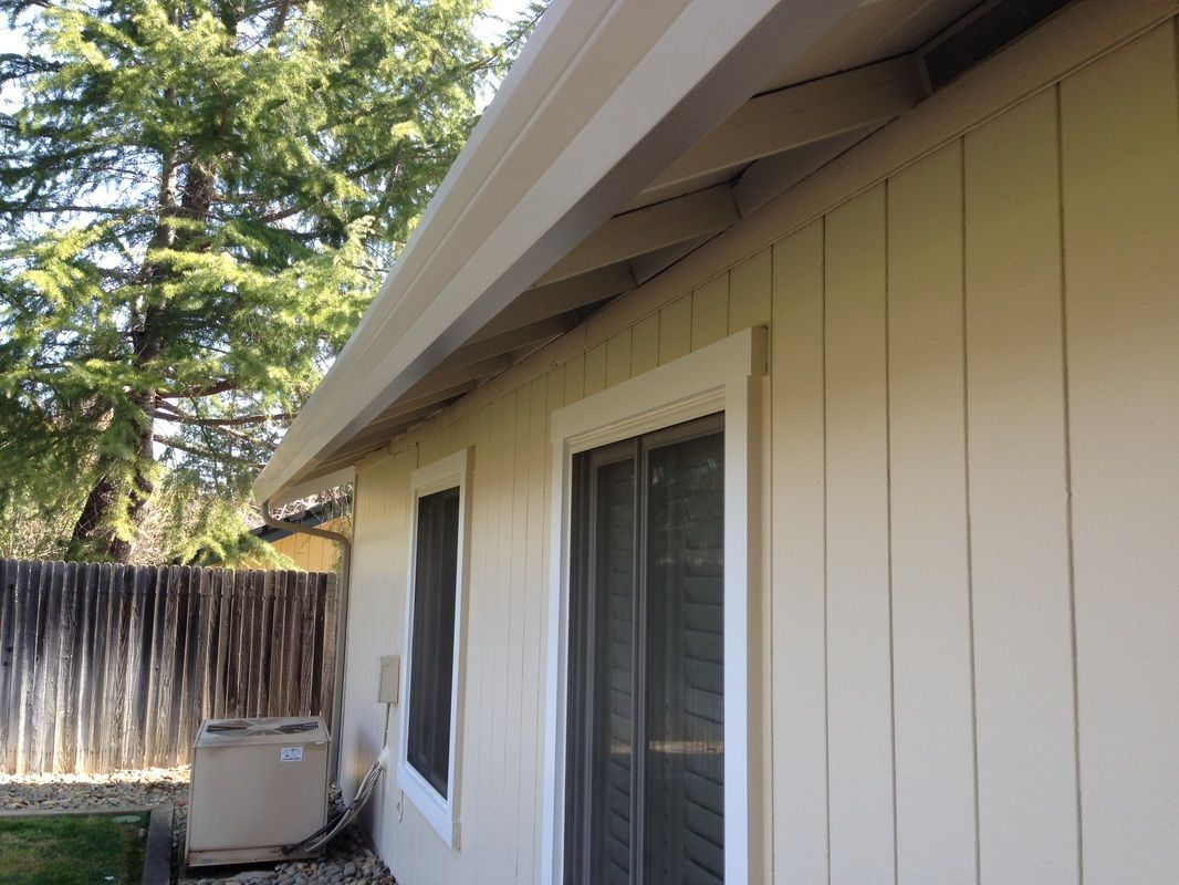 A white house with a sliding glass door and a white gutter