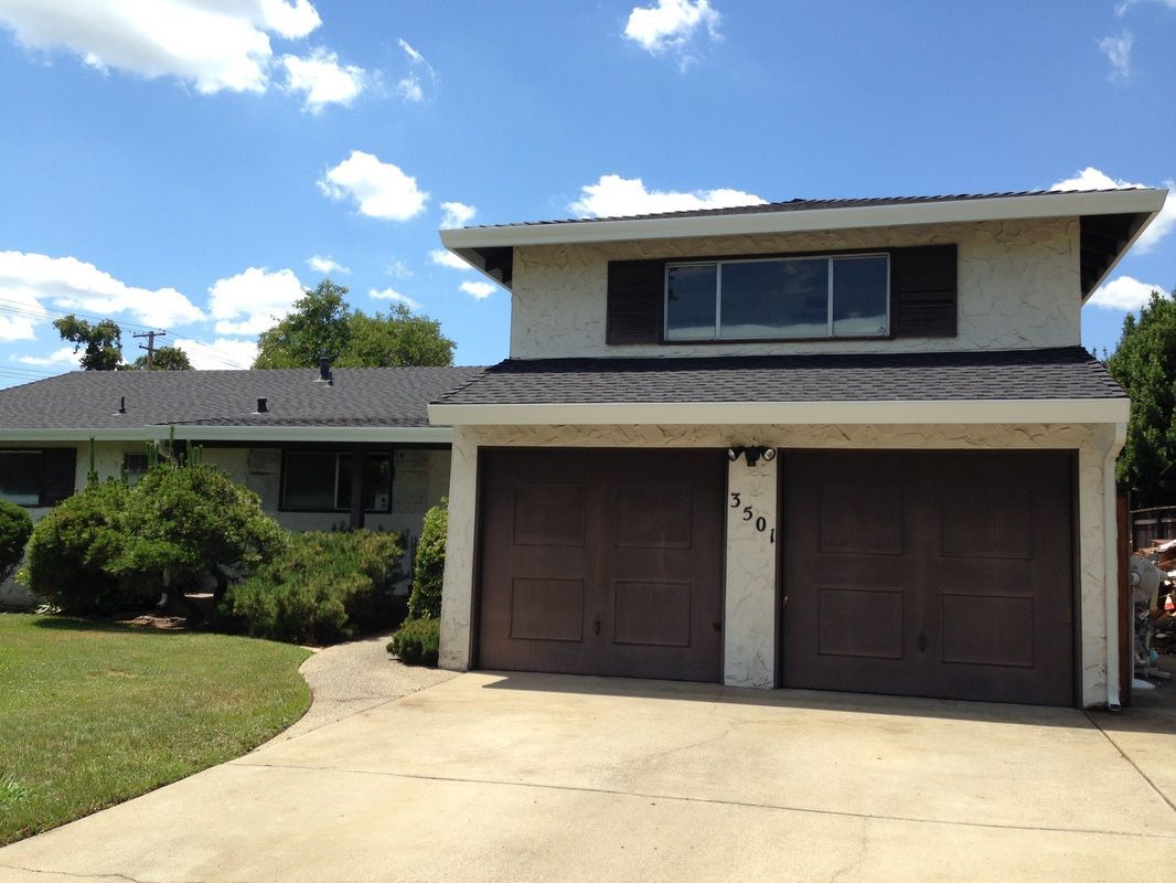 A white house with two brown garage doors on a sunny day