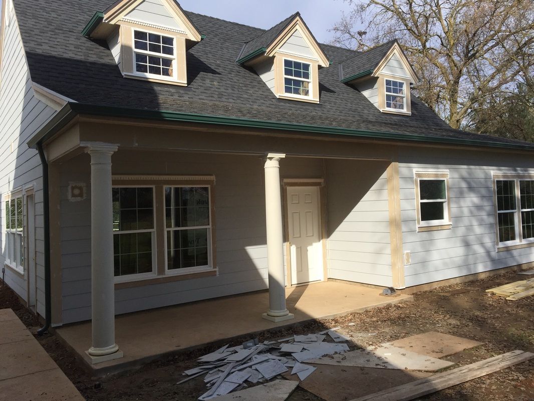 A white house with a porch and a gray roof