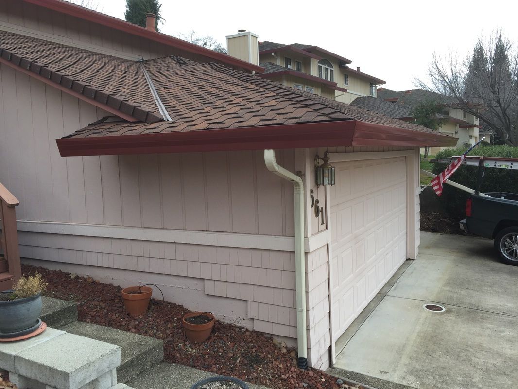 A white house with a red roof and a white gutter