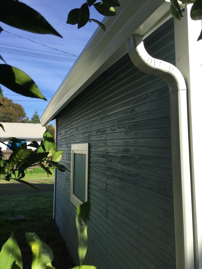 A house with a white gutter on the side of it