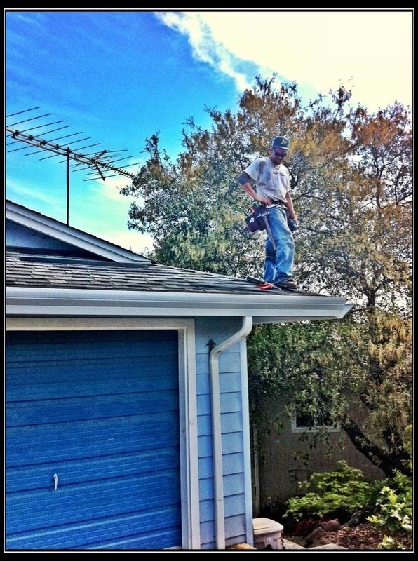 A man is standing on the roof of a blue house