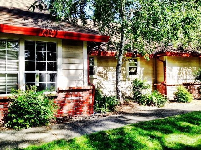 A white house with a red roof and a brick wall
