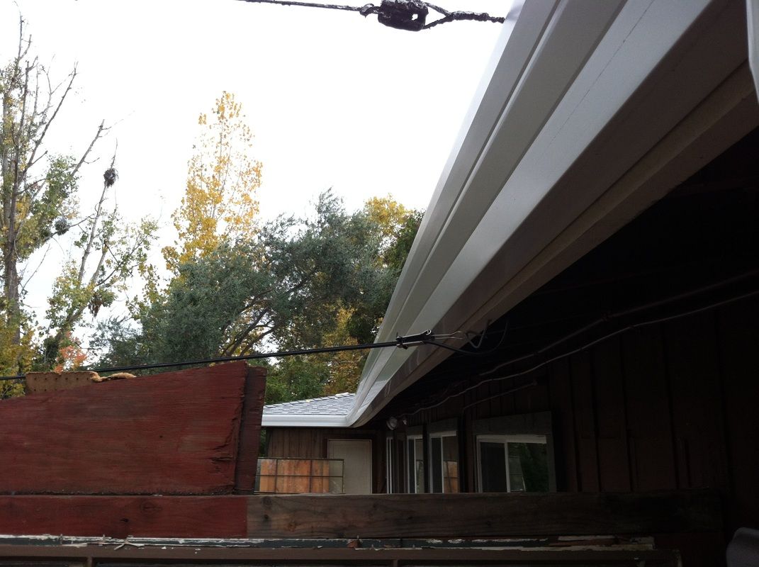 A white gutter is hanging from the side of a house.