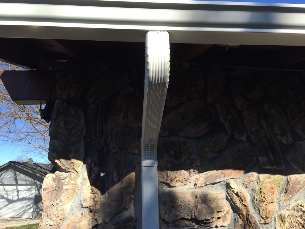 A white pole is sitting in front of a stone wall.