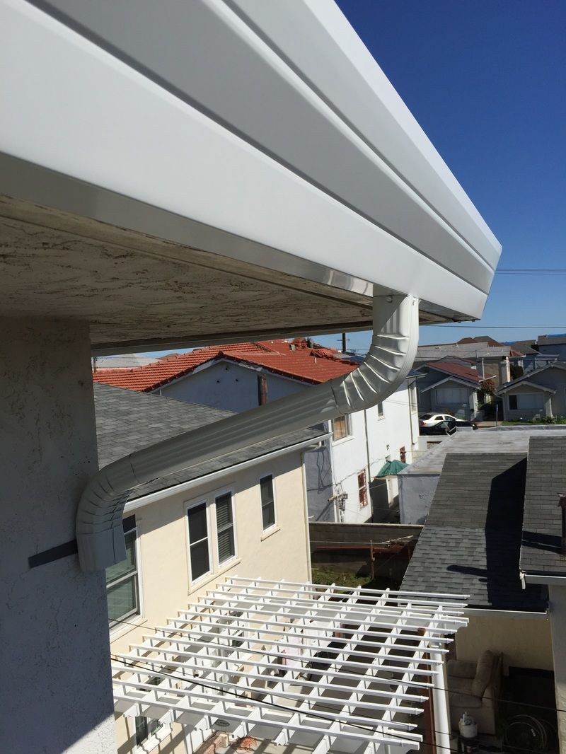 A white gutter is attached to the side of a building