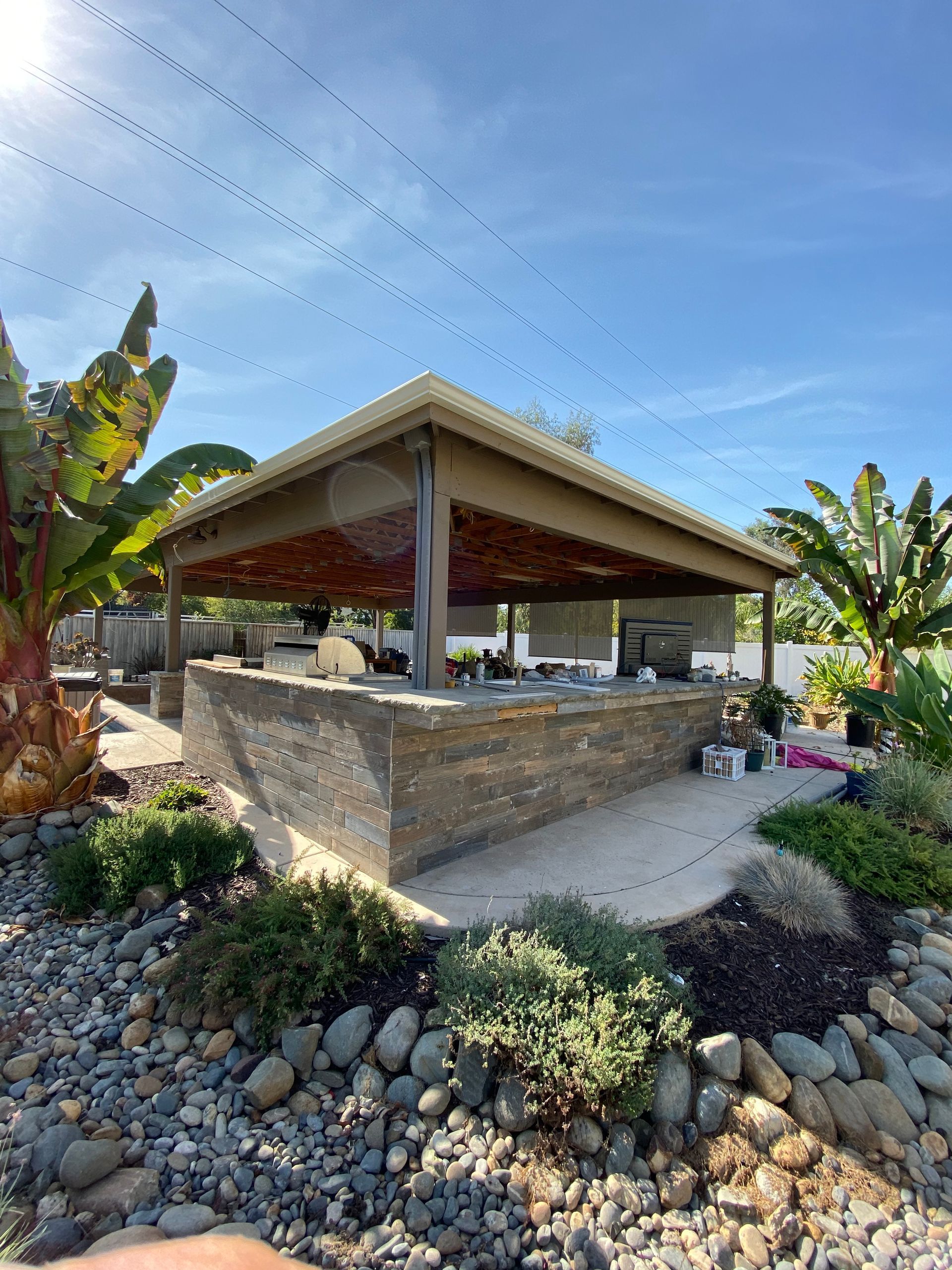 A man is standing in front of a pavilion in the middle of a rocky area.