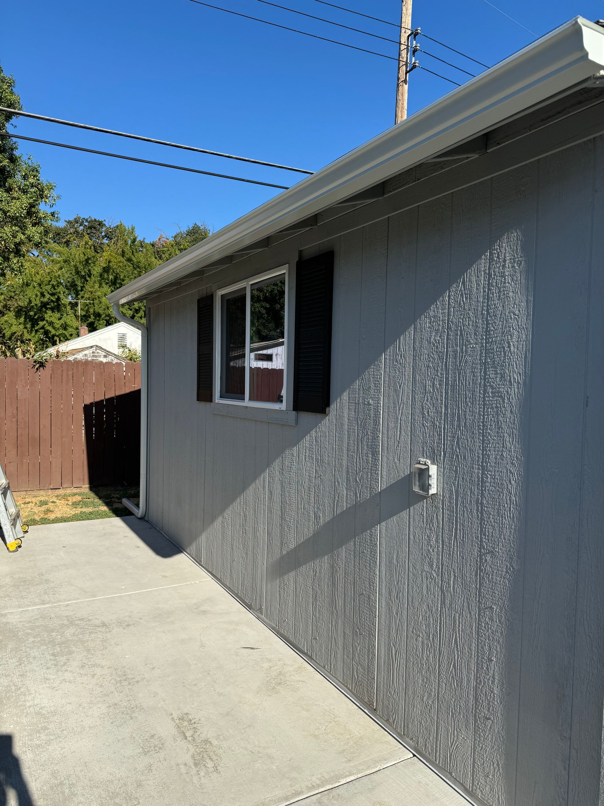 A gray house with black shutters and a window