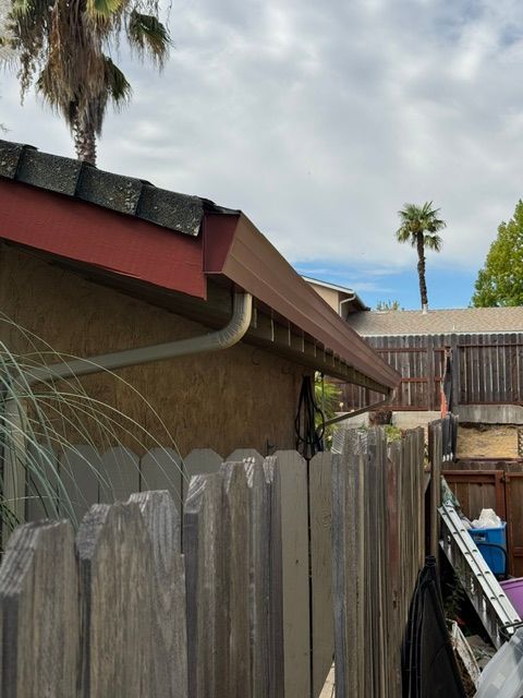 A wooden fence surrounds a house with a palm tree in the background