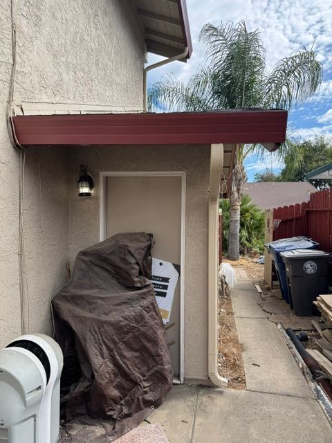 A house with a red roof and a trash can in front of it