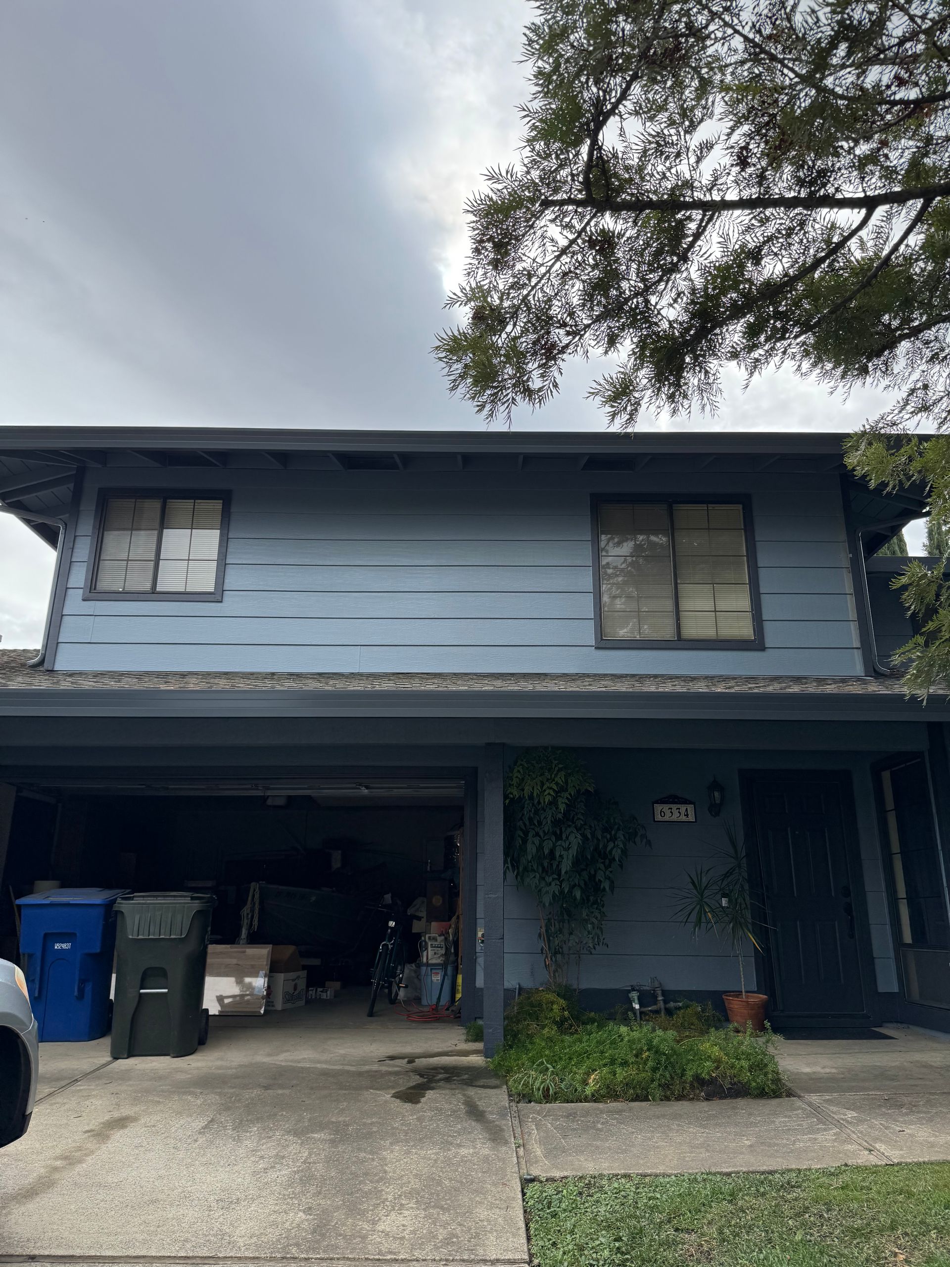A blue house with a garage and a car parked in front of it.
