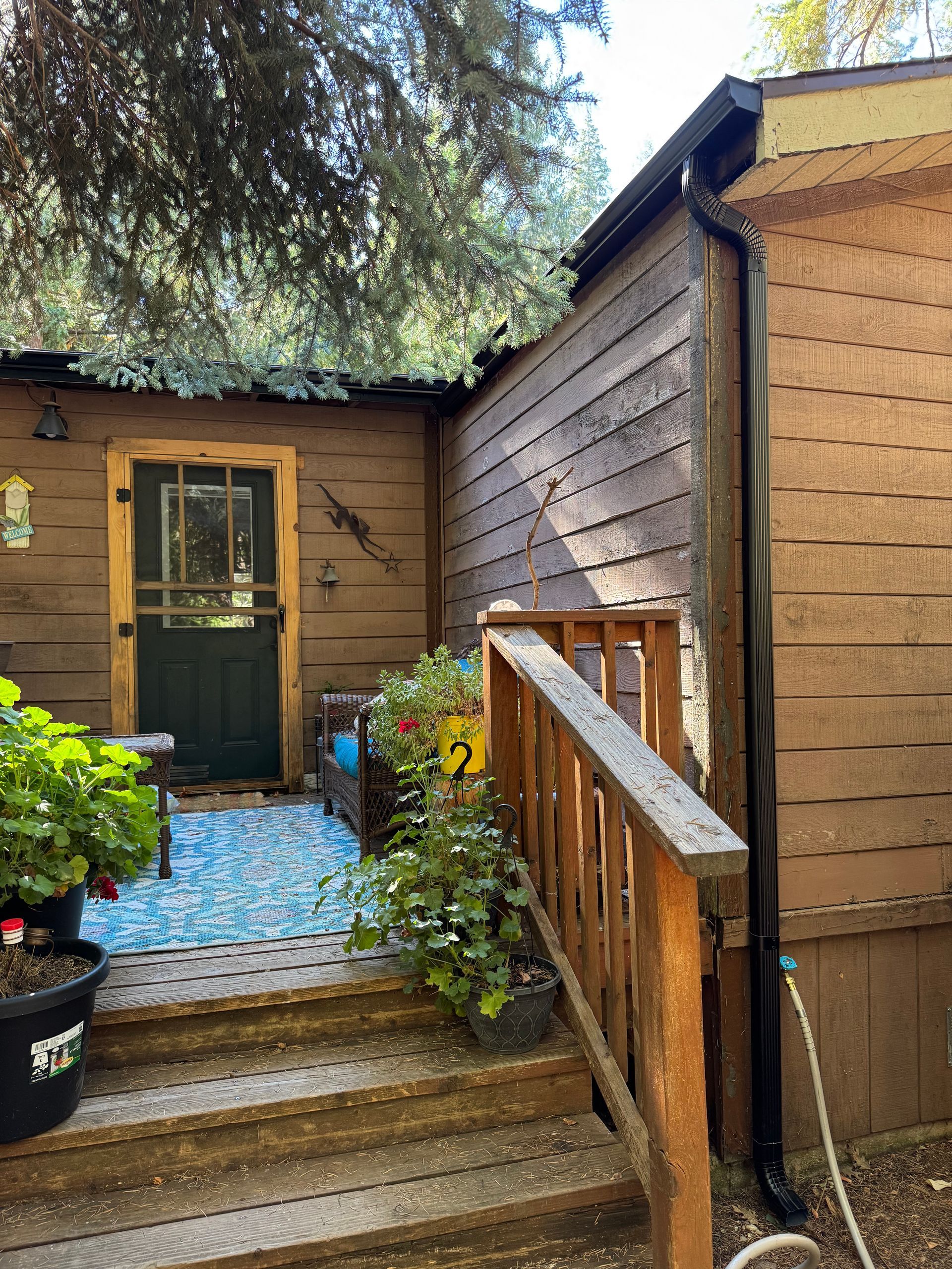 A wooden house with a porch and stairs leading to it.