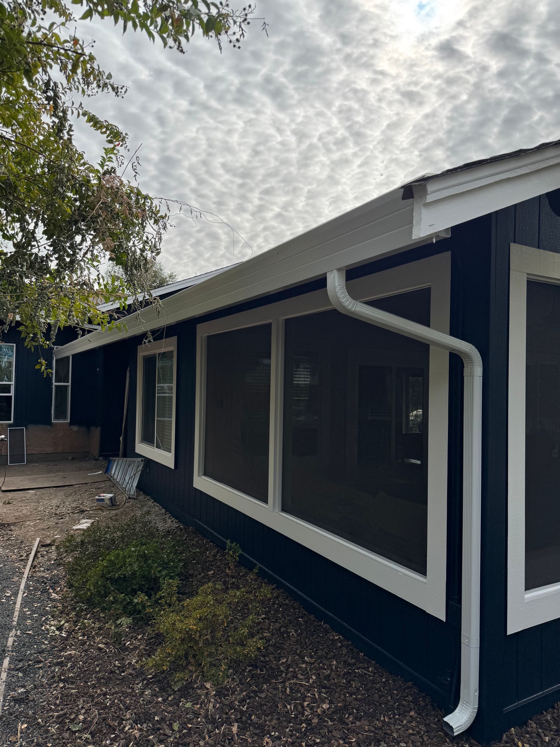 A black and white house with a screened in porch and a white gutter.