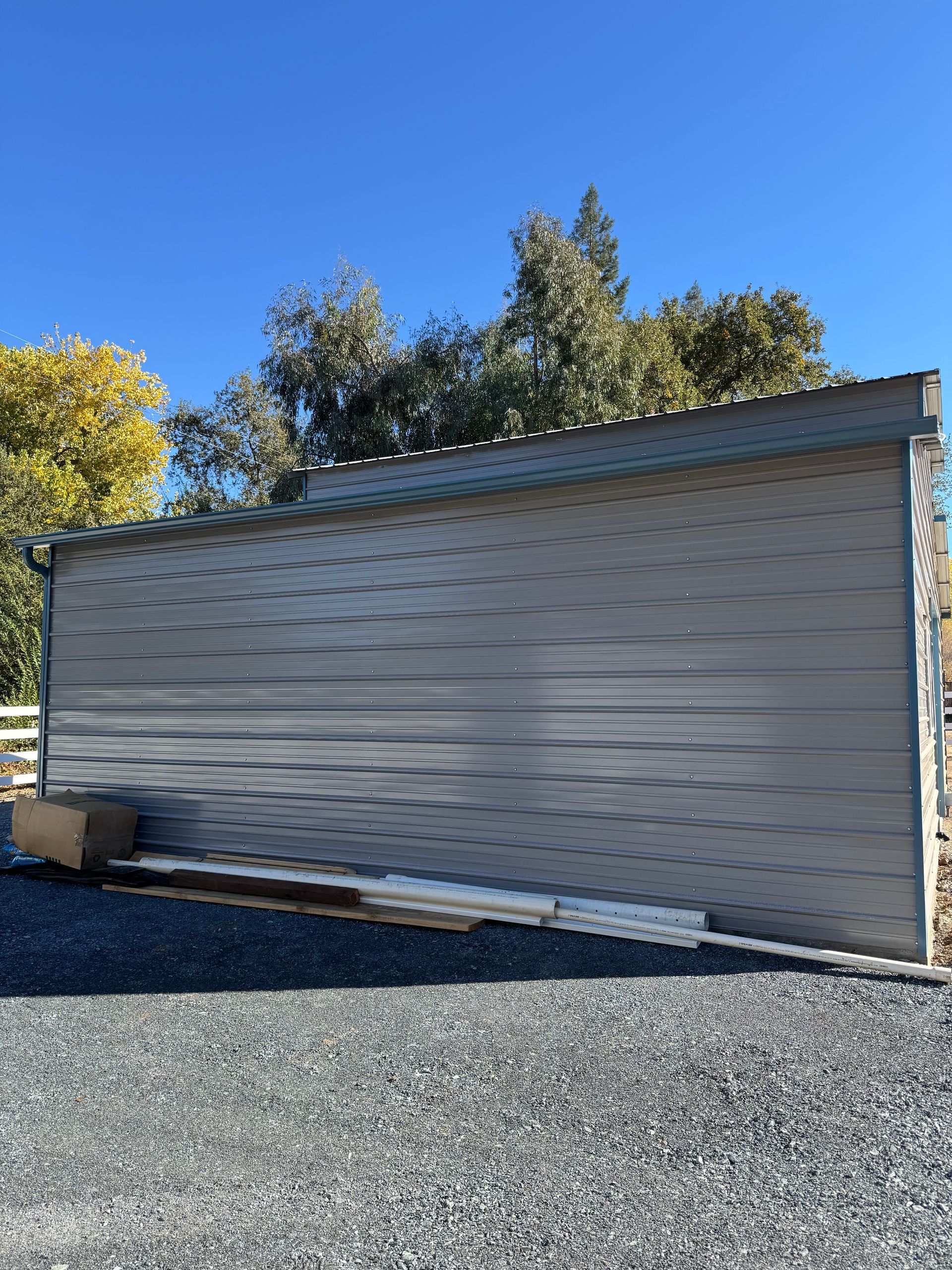 A large garage door is sitting on top of a gravel driveway.