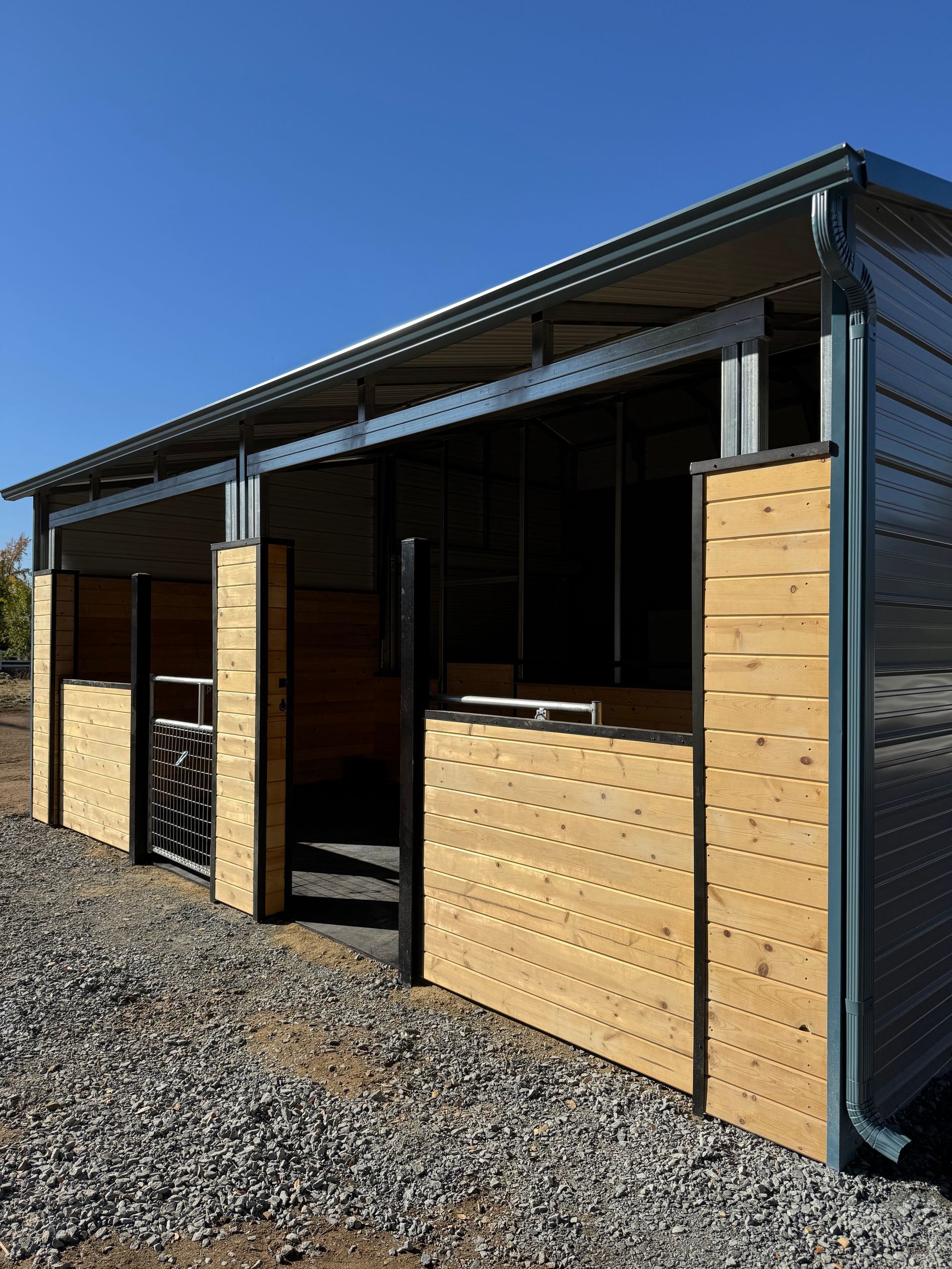 A horse stable with wooden walls and a metal roof