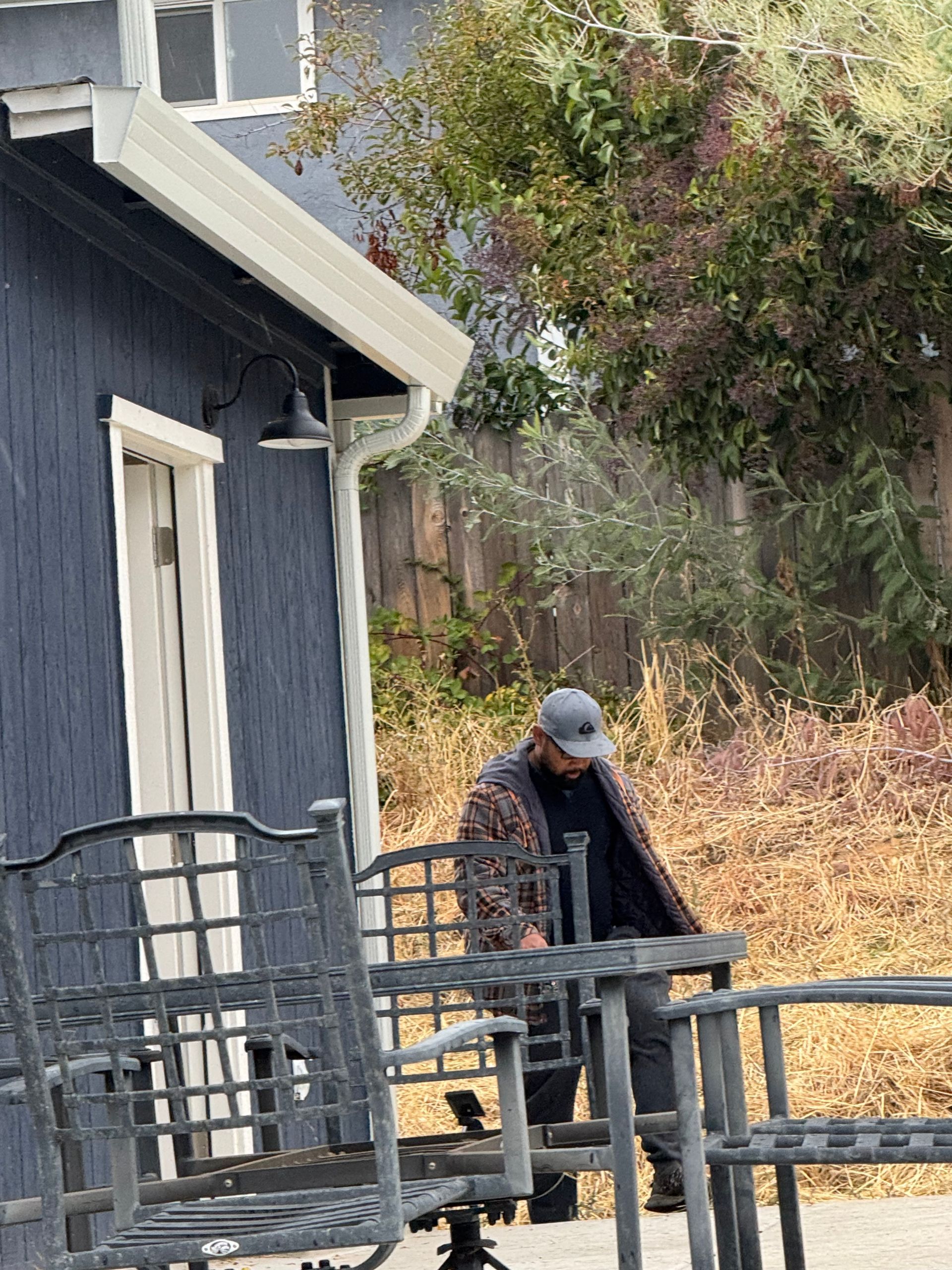 A man is standing next to a row of chairs in front of a house.